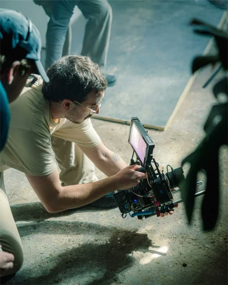 A filmmaker crouched behind a camera rig on set