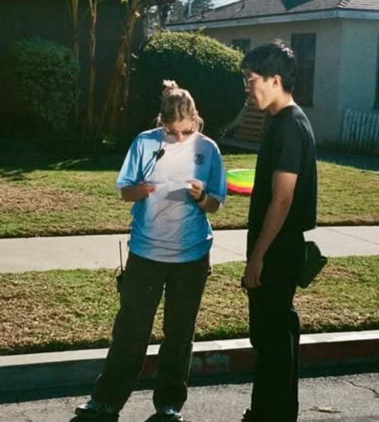 Two people reading a script on a sunny sidewalk