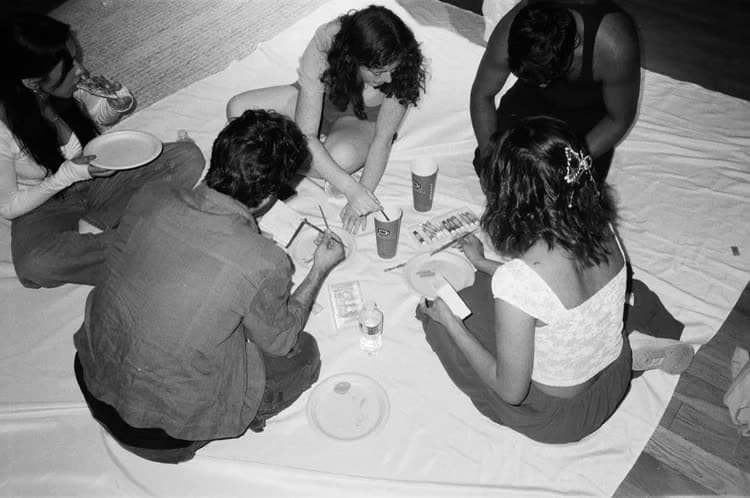 Four members sitting on a picnic blanket sharing snacks